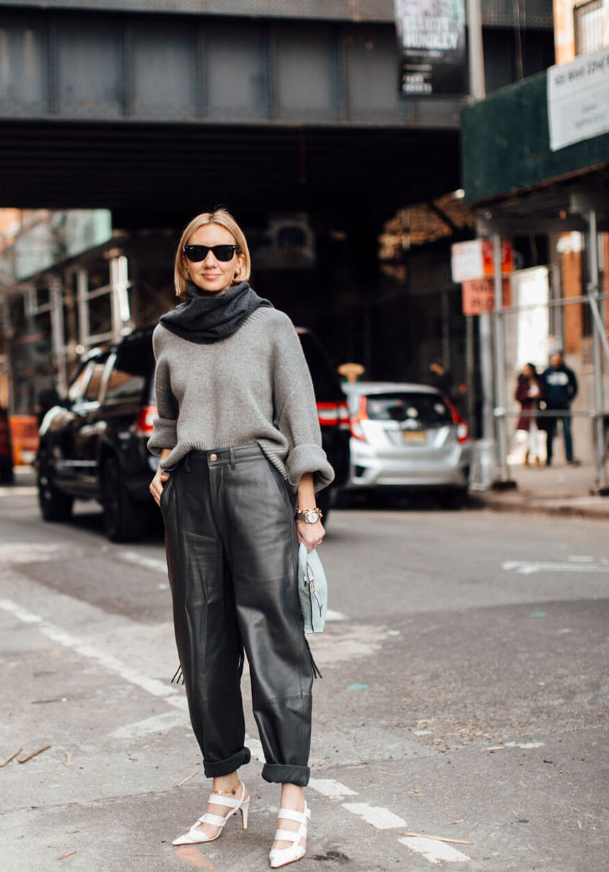 Frau trägt eine graue Lederhose kombiniert mit einem grauen Pullover als Casual Look